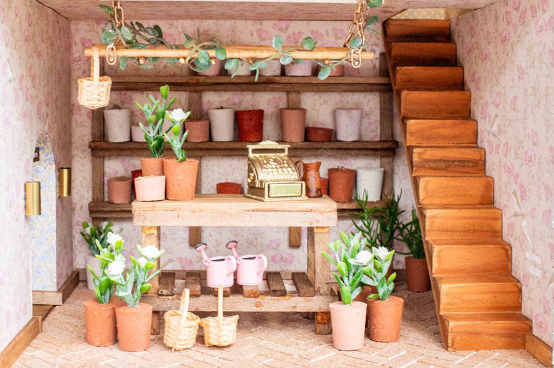 Miniature indoor setting with shelves, plants, and a staircase.