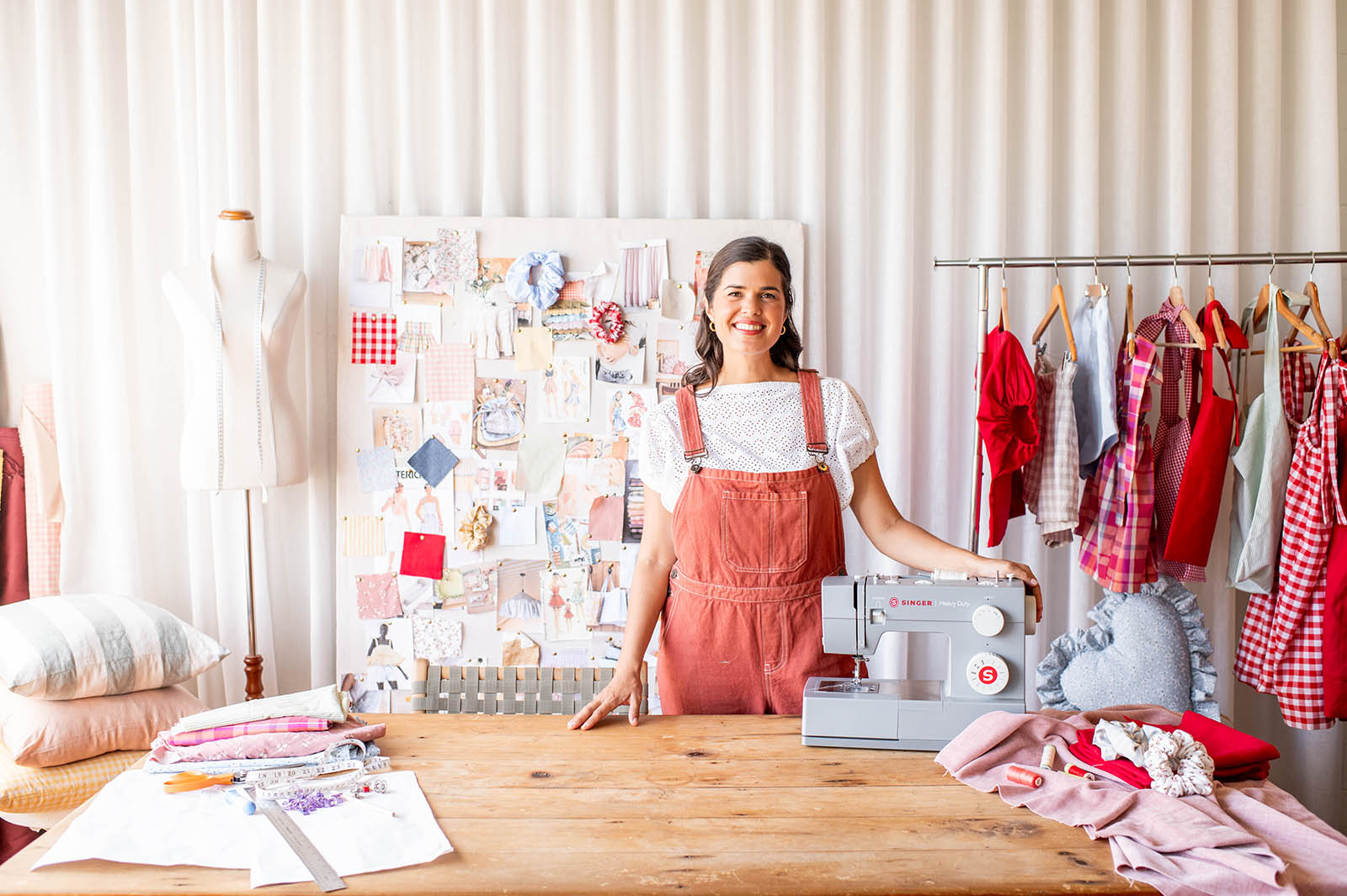 Woman in a sewing studio with a sewing machine and fabric on a table.